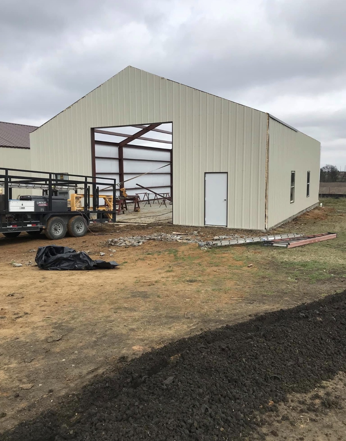 Custom metal shop exterior taking shape with walk-in and overhead-door openings