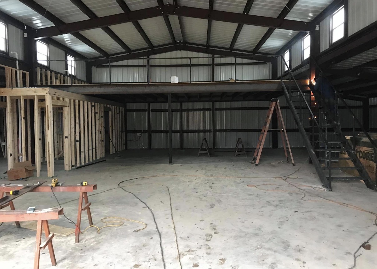 Red-iron shop interior with a custom mezzanine, stairs and framed rooms